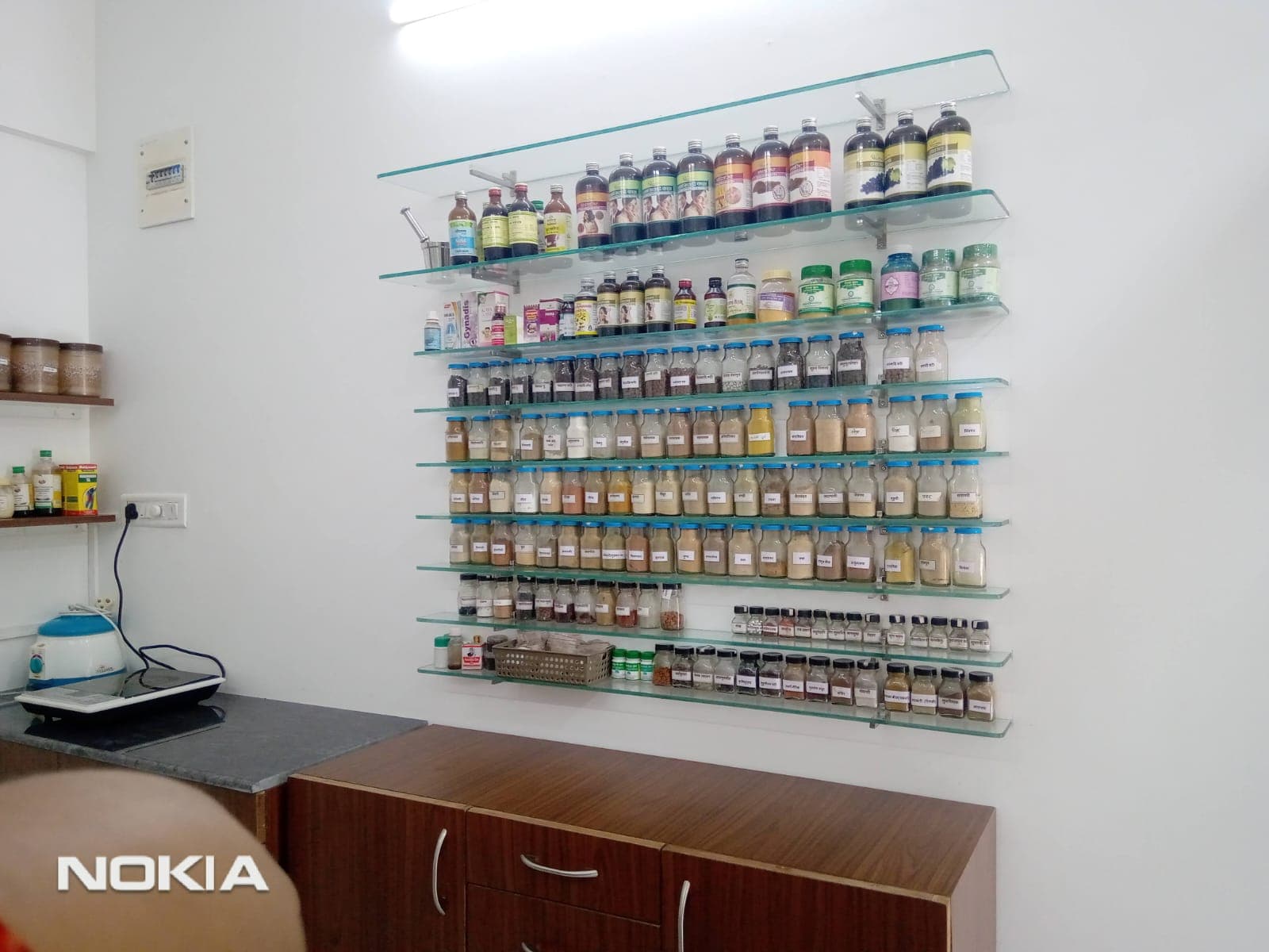 In-house Ayurvedic pharmacy shelves with classical formulations and churnas